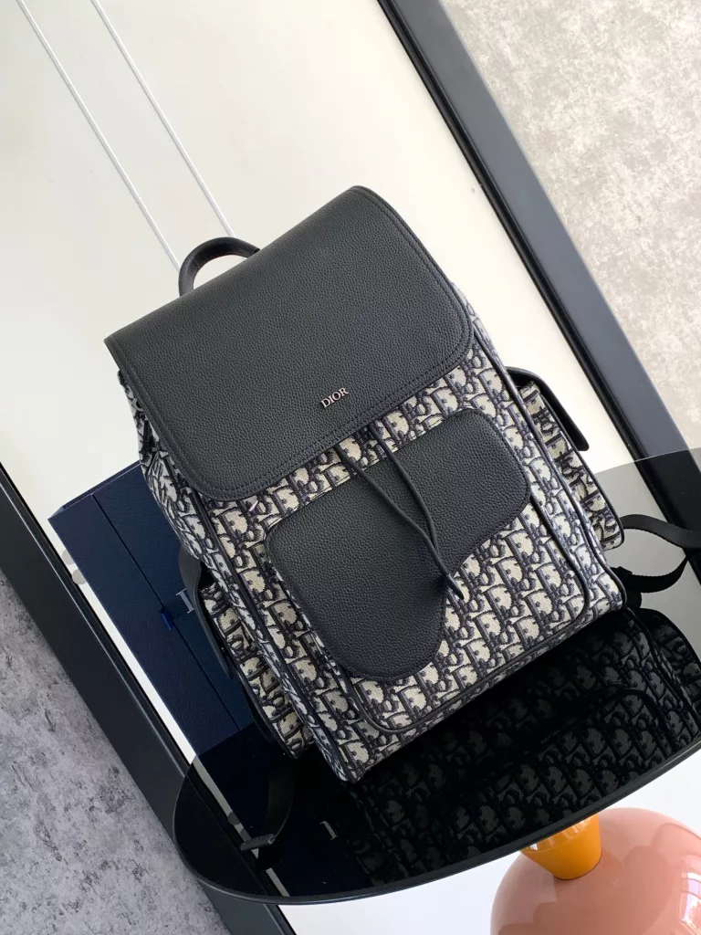 The Saddle backpack features a stylish, original design that highlights the saddle style. Crafted in beige and black Oblique printed jacquard fabric, decorated with black grain ox-leather details, the front is decorated with the 