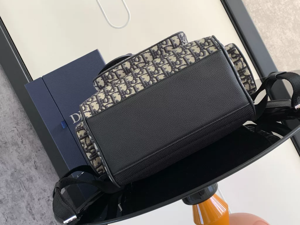 The Saddle backpack features a stylish, original design that highlights the saddle style. Crafted in beige and black Oblique printed jacquard fabric, decorated with black grain ox-leather details, the front is decorated with the 