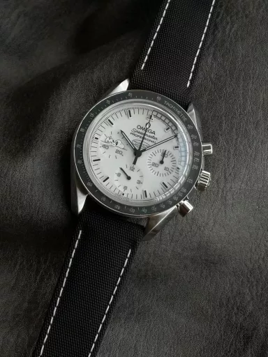OM Exploration Magazine: Omega Speedmaster 311.32.42.30.04.003 watch (Snoopy Limited Edition), stainless steel case with black nylon leather strap, black lacquered hands, covered with Super-LumiNova luminous coating, equipped with manual mechanical chronograph movement, 42 mm.