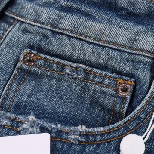 Margiela MM6 patch distressed denim trousersCustomized denim rough twill cotton satin, combined with rubbing and pressing cat whisker technology and gun painting cat whisker technology, manual rubbing is preferred in specific areas to achieve natural wrinkle effects, and then specific tools are used to draw cat whisker-shaped textures to maximize visual effects, the holes are made with rotten edge hanging rotten technology, and the natural rotten edge effect is achieved by rubbing the edges through physical wear, and the fiber hairiness and color difference are removed through the combination of high-temperature steam and sandpaper, so that the jeans present unique holes and wear effects, heavy washing and spraying dirty process, through physical and chemical means, use a spray gun to evenly spray water-soluble dyes on the denim fabric, the dye will form natural spots and stains on the surface of the fabric, simulating the wear marks after long-term wear, customized accessories, loose version