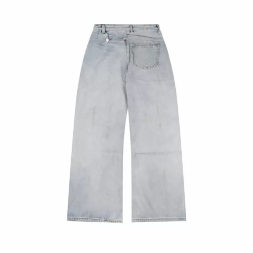 Margiela MM6 patch distressed denim trousersCustomized denim rough twill cotton satin, combined with rubbing and pressing cat whisker technology and gun painting cat whisker technology, manual rubbing is preferred in specific areas to achieve natural wrinkle effects, and then specific tools are used to draw cat whisker-shaped textures to maximize visual effects, the holes are made with rotten edge hanging rotten technology, and the natural rotten edge effect is achieved by rubbing the edges through physical wear, and the fiber hairiness and color difference are removed through the combination of high-temperature steam and sandpaper, so that the jeans present unique holes and wear effects, heavy washing and spraying dirty process, through physical and chemical means, use a spray gun to evenly spray water-soluble dyes on the denim fabric, the dye will form natural spots and stains on the surface of the fabric, simulating the wear marks after long-term wear, customized accessories, loose version