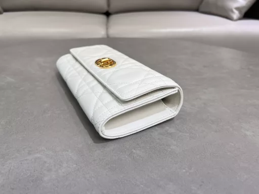 New to the Cruise 2025 collection, the Miss Caro Top Handle Clutch is an everyday piece that exudes sophistication. Crafted from burgundy lambskin leather with oversized cannage stitching, the flap features a vintage gold-finish metal knob-style CD buckle, inspired by the closure of a Christian Dior perfume bottle, and a compartment for storing a variety of daily necessities. With a foldable top handle, it can be carried by hand, enhancing the sophisticated look.