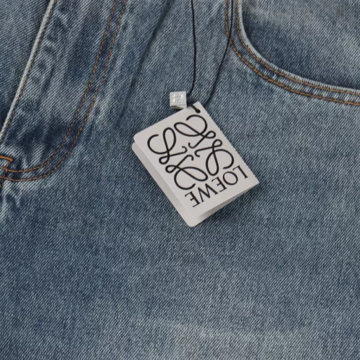 Loewe Anagram tapered denim pantsCustomized elegant rough twill denim material, laser laser technology, using high-energy laser beam to accurately process the material surface, by controlling the intensity, frequency and scanning speed of the laser beam, high-precision Loewe Anagram engraving can be achieved, using sand frying hand rubbing technology, through processing on the sand frying machine, the surface of the jeans will fade and wear naturally, and then the surface of the jeans will be physically damaged by hand using special tools, maintaining the original texture and details while increasing its uniqueness, heavy washing and whitening process, through physical and chemical means, the denim fabric is deeply processed multiple times, so that the surface of the pants presents a gray effect, and then the denim fabric is polished by machine to make the surface of the pants have a worn effect, customized accessories, fit version