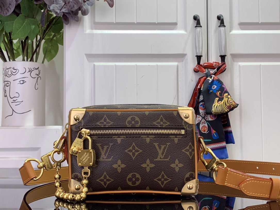 The mini soft luggage is made of Monogram coated canvas with natural cowhide leather trim. It features a gold ball chain and a new decorative padlock engraved with the 
