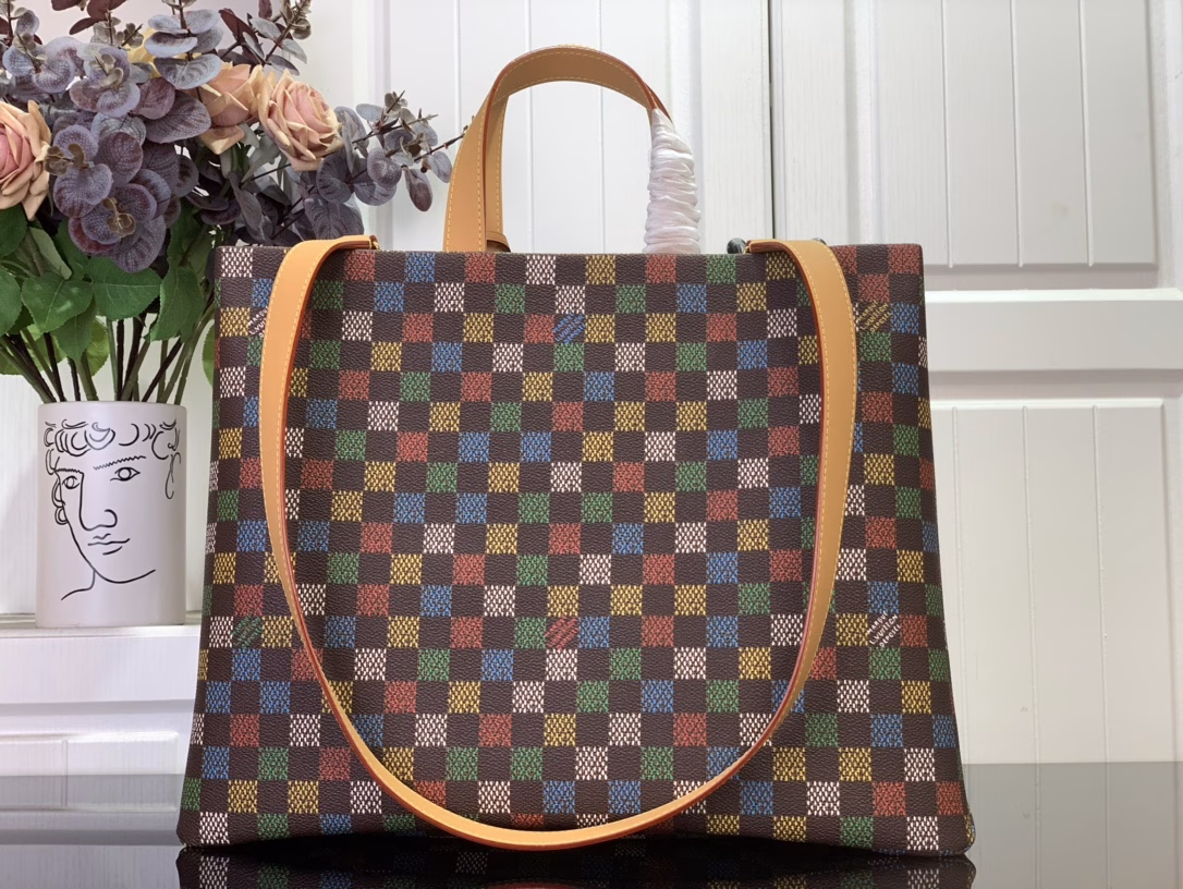 The Shopper Tote is inspired by the classic Louis Vuitton shopping bag, featuring the same clean lines and contrasting Louis Vuitton monogram. This bag is made of LVers Damier Ebene coated canvas with Pharrell Williams' colorful reinterpretation of the Damier pattern (inspired by the classic design created by Georges Vuitton in 1888). Two top handles and a removable shoulder strap provide flexible carrying options, combining practicality and unique charm.