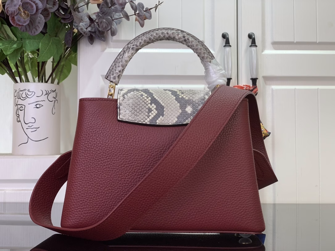 The Capucines bb bag features light blue Taurillon leather for a sophisticated feminine appeal, juxtaposed with precious Karung leather on the flap and top handle. Although soft to the touch, Karung leather is extremely durable, making it long-lasting. In addition to the iconic top handle, the Capucines also features a wide, removable shoulder strap.